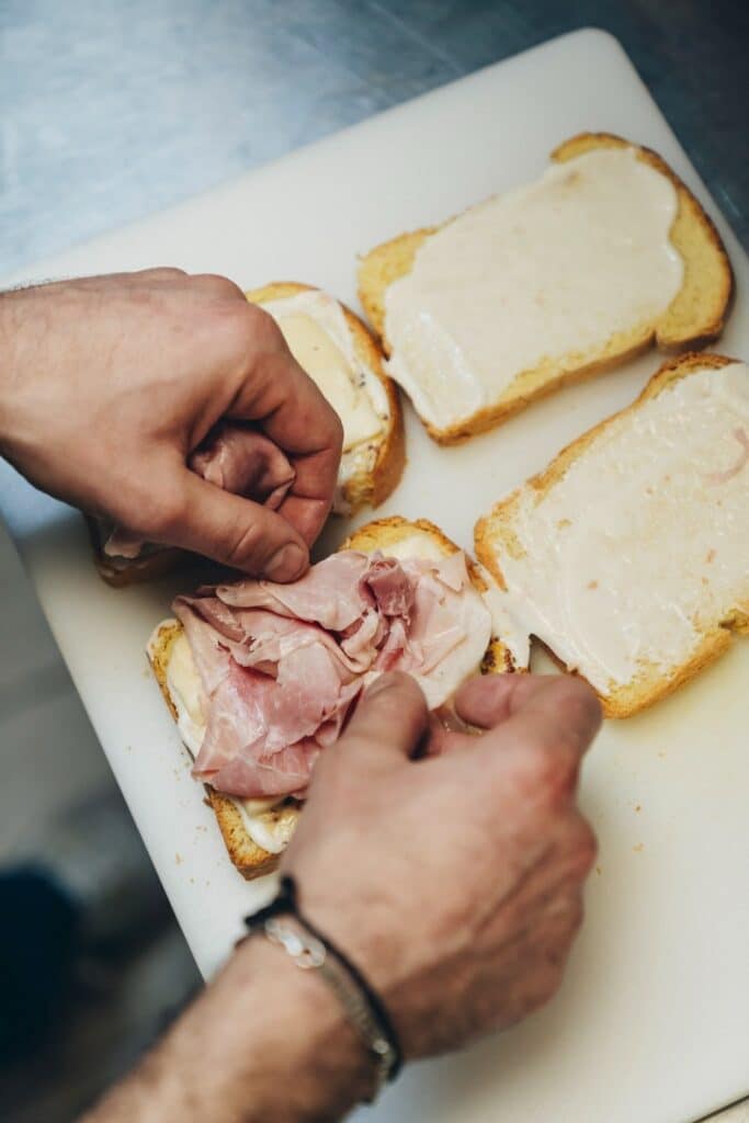 mani che preparano un croque madame con il prosciutto