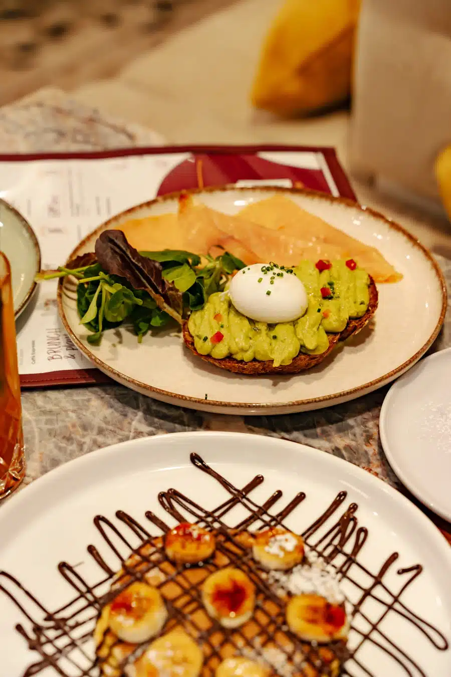 avocado toast su un piatto e pancakes sull'altro