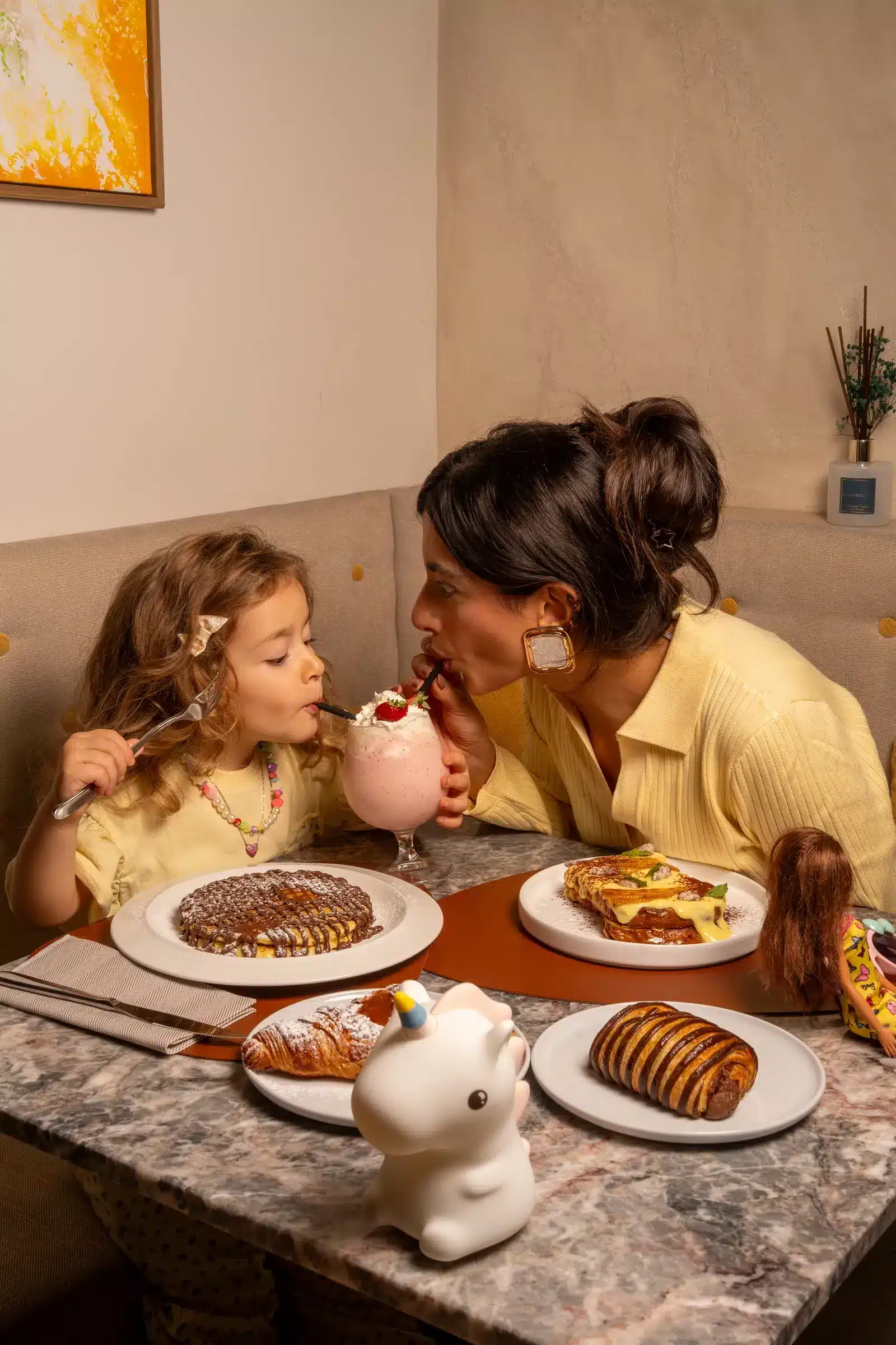 Mamma e bambina a colazione con frappè e cornetti