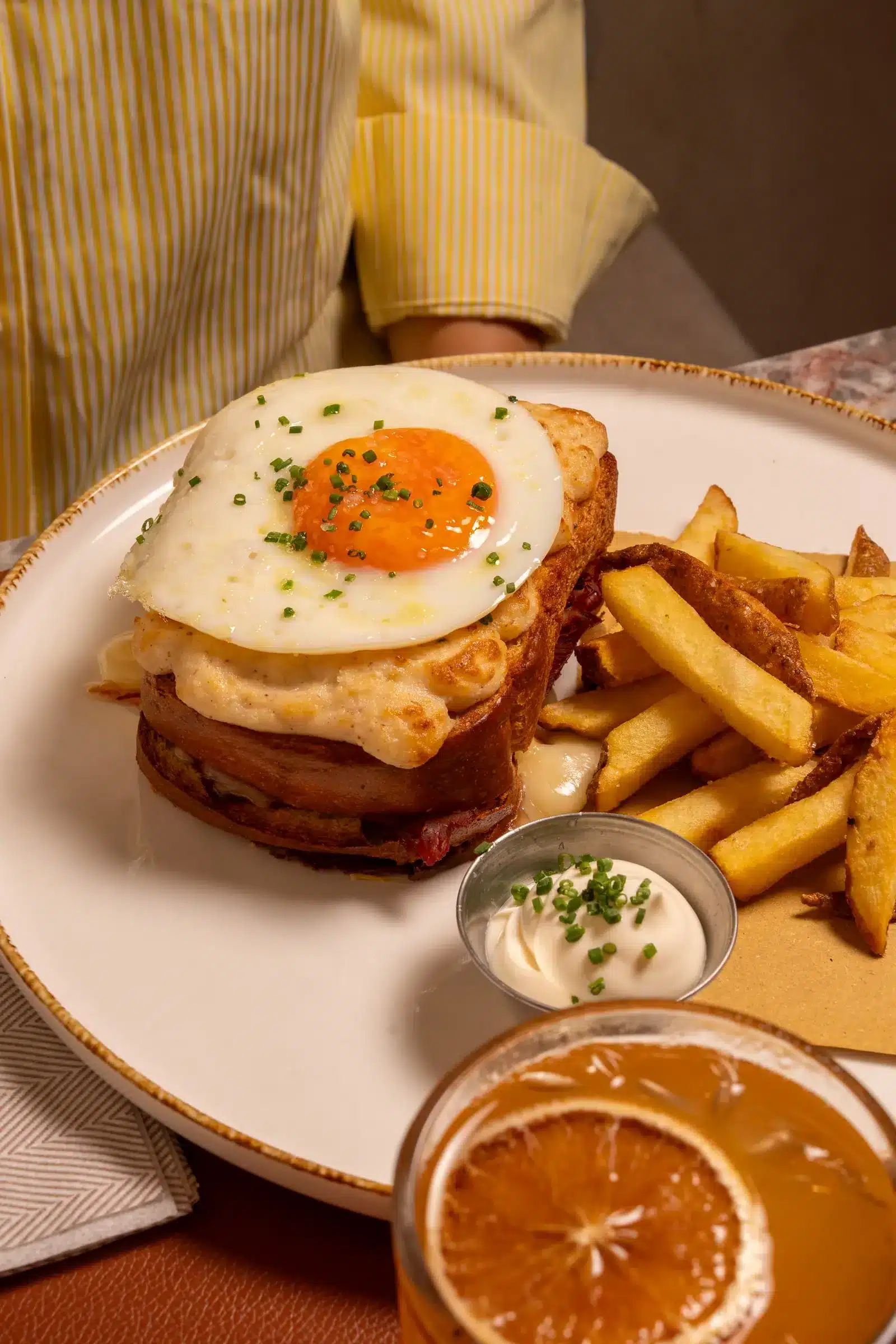 Croque madame con uovo, patatine e succo d'arancia