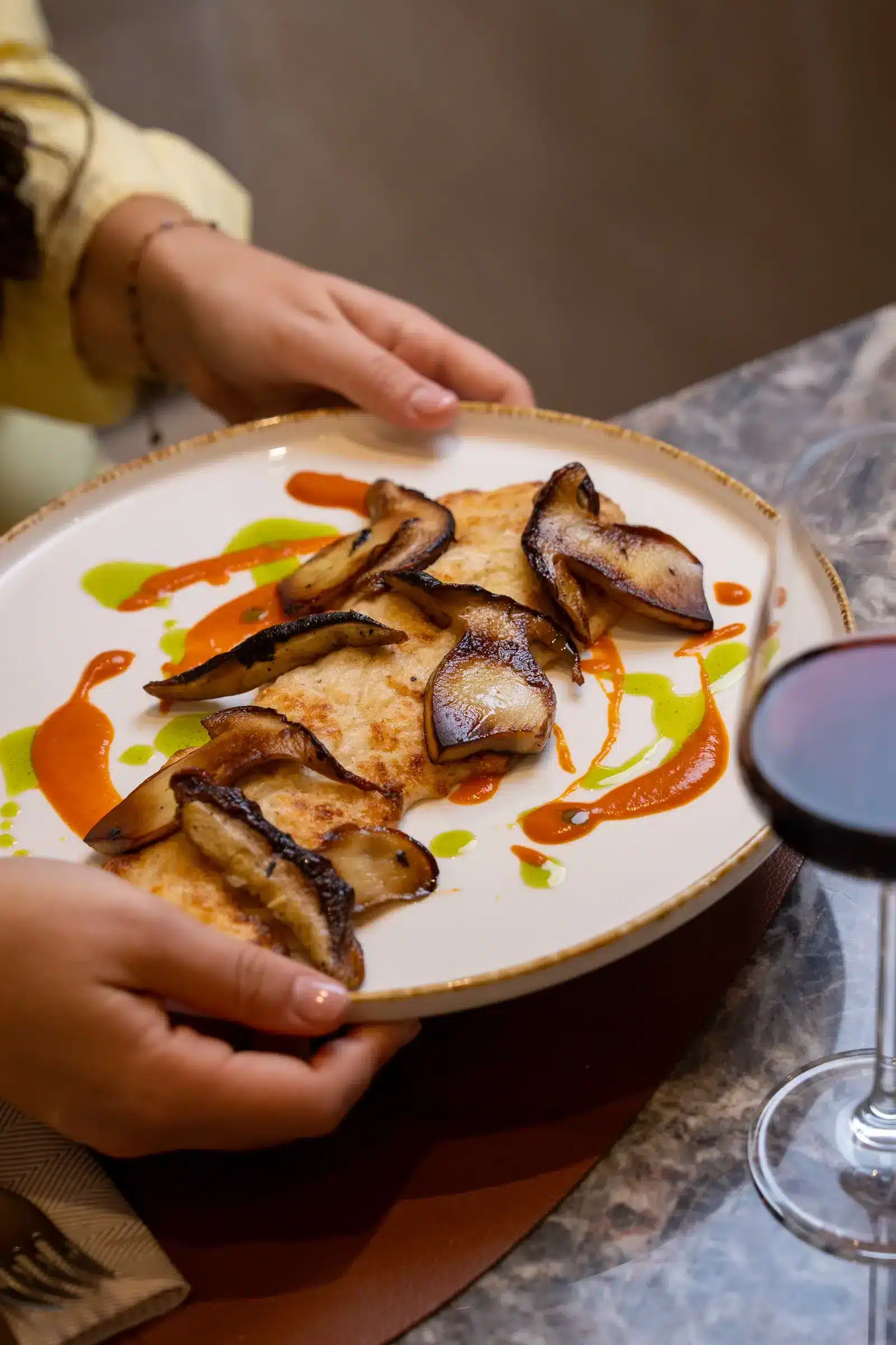 Piatto con funghi e salse servito con un calice di vino rosso