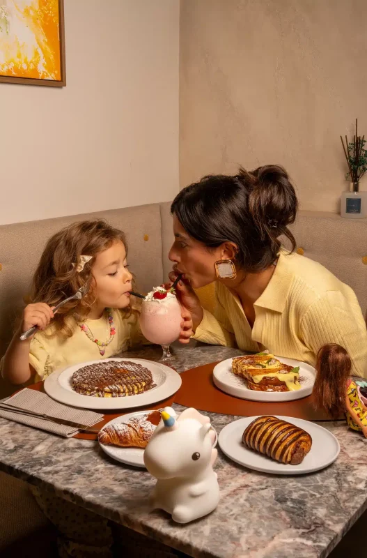 Mamma e bambina a colazione con frappè e cornetti